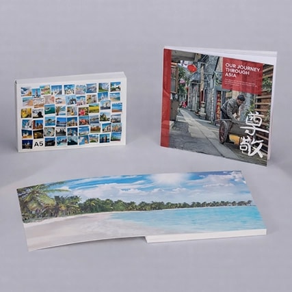 Three photo books, one open, featuring travel and scenic images on their covers and pages.