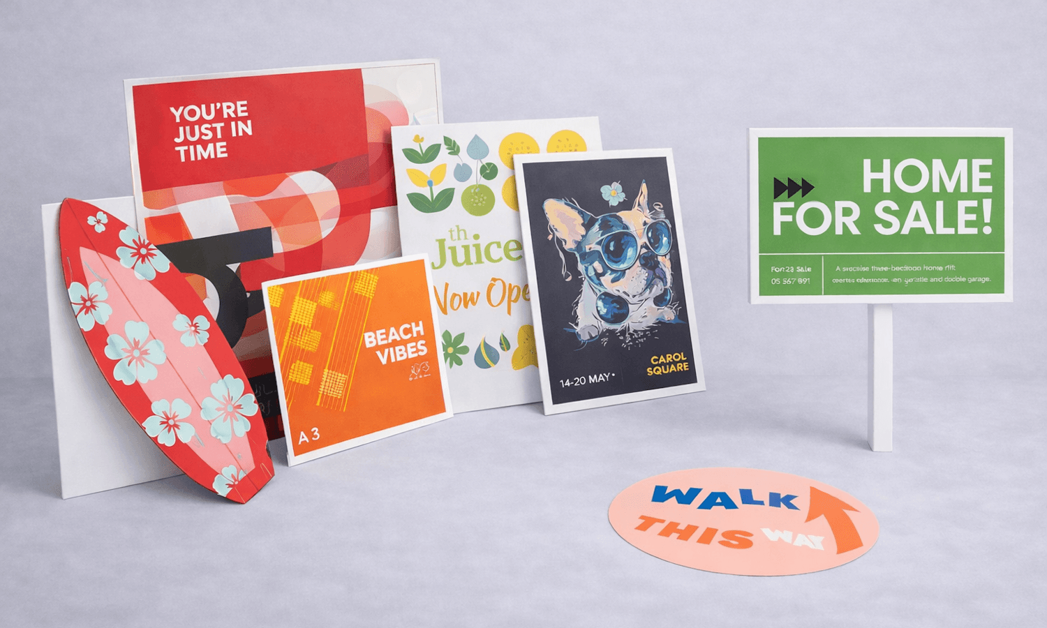 A variety of colourful printed signs and posters displayed on a light grey surface.