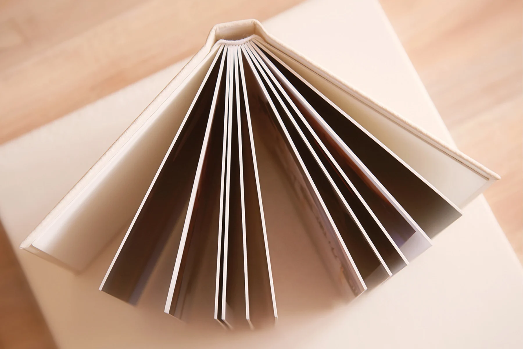 An open book resting on a table, displaying several pages that are fanned out