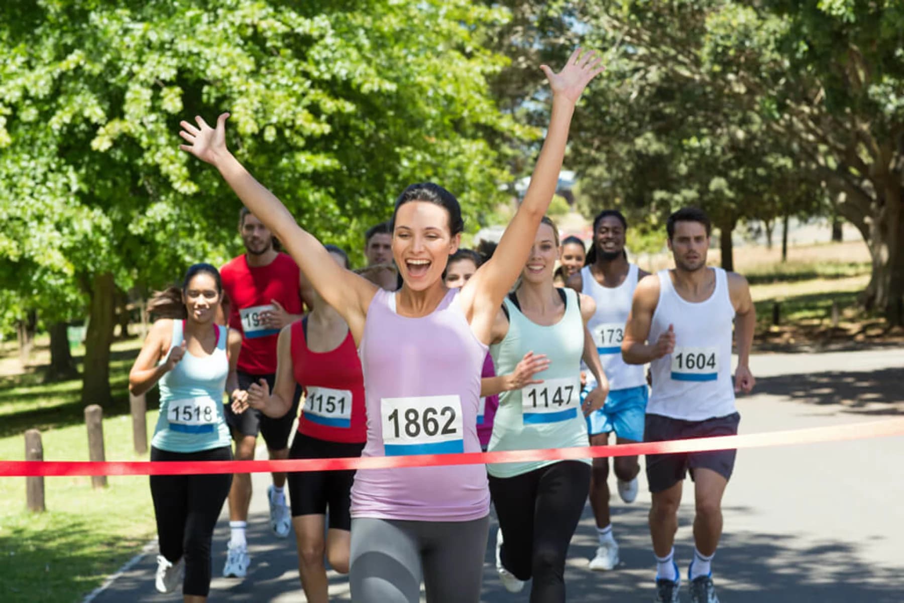 A woman triumphantly crosses the finish line of a marathon, celebrating her achievement