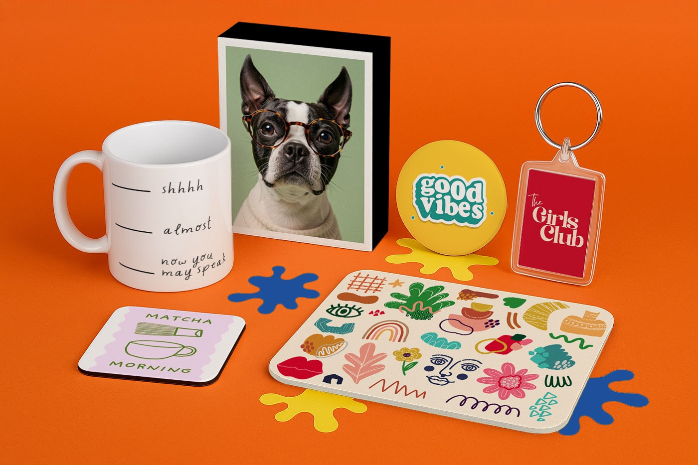 A mug, coasters, mousepad, keychain, pins, and dog photo on an orange background.