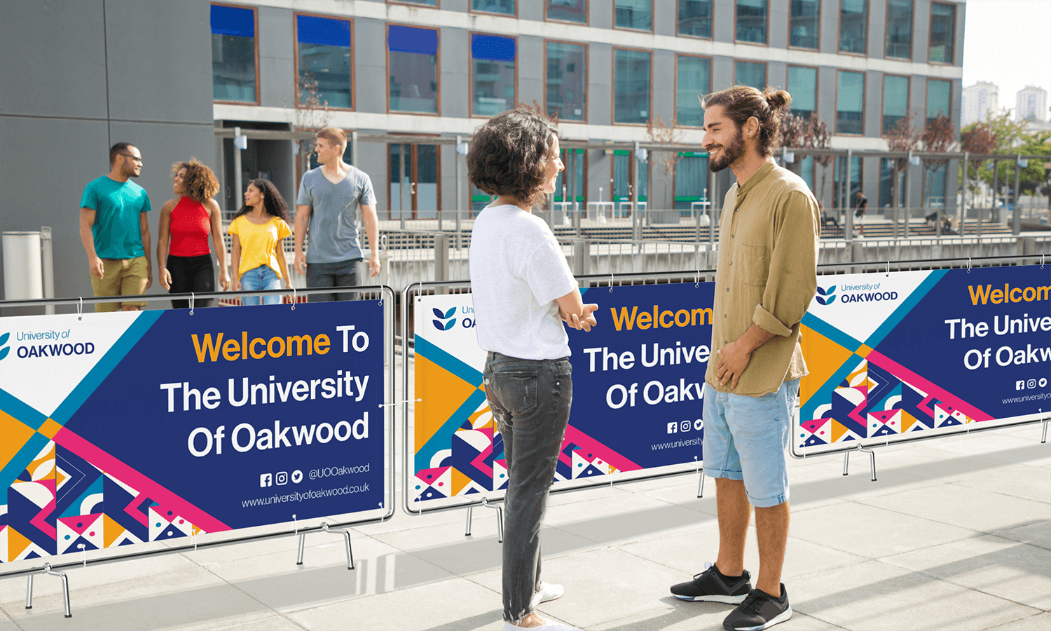 Two people talking outside a building near University of Oakwood welcome fence banner signs.