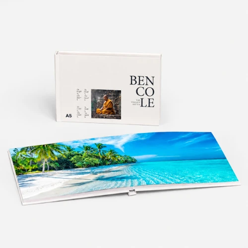 A white photo book with a cover image and an open page showing a tropical beach scene.