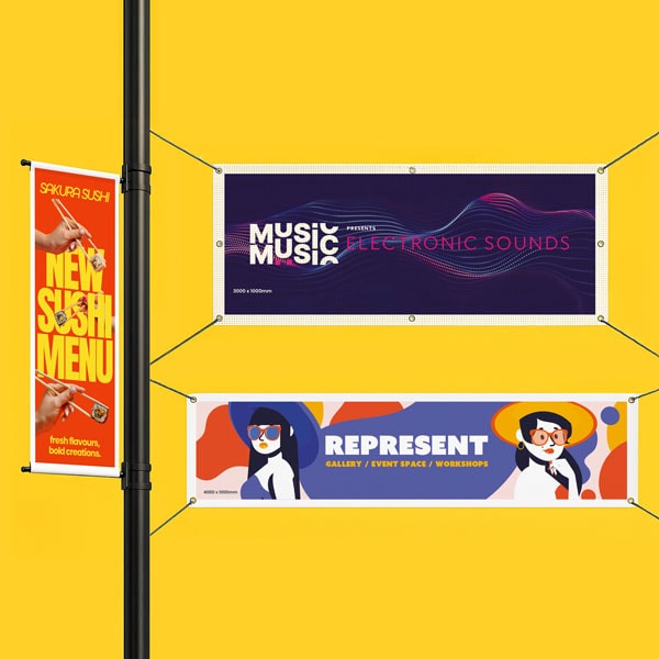 Three colorful event and menu banners hang against a bright yellow wall and black pole.