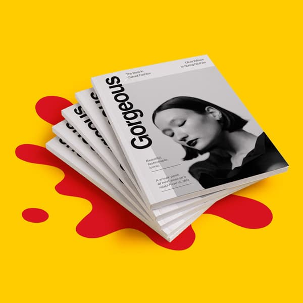 Stack of magazines titled “Gorgeous” on a yellow background with red abstract shapes.