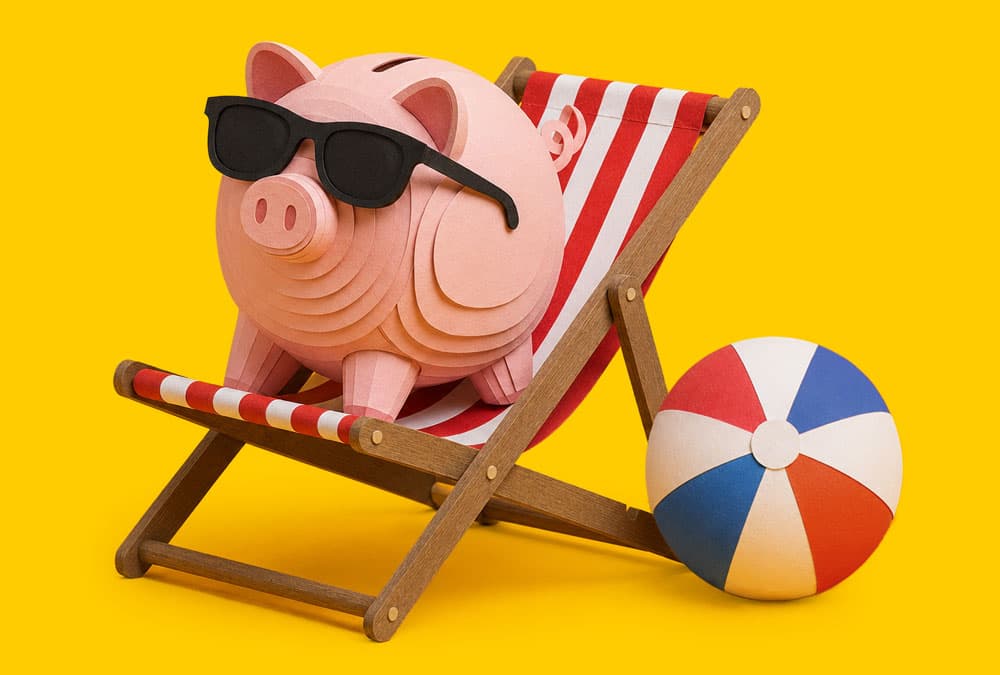 Piggy bank wearing sunglasses sits on a deck chair next to a beach ball on yellow background.