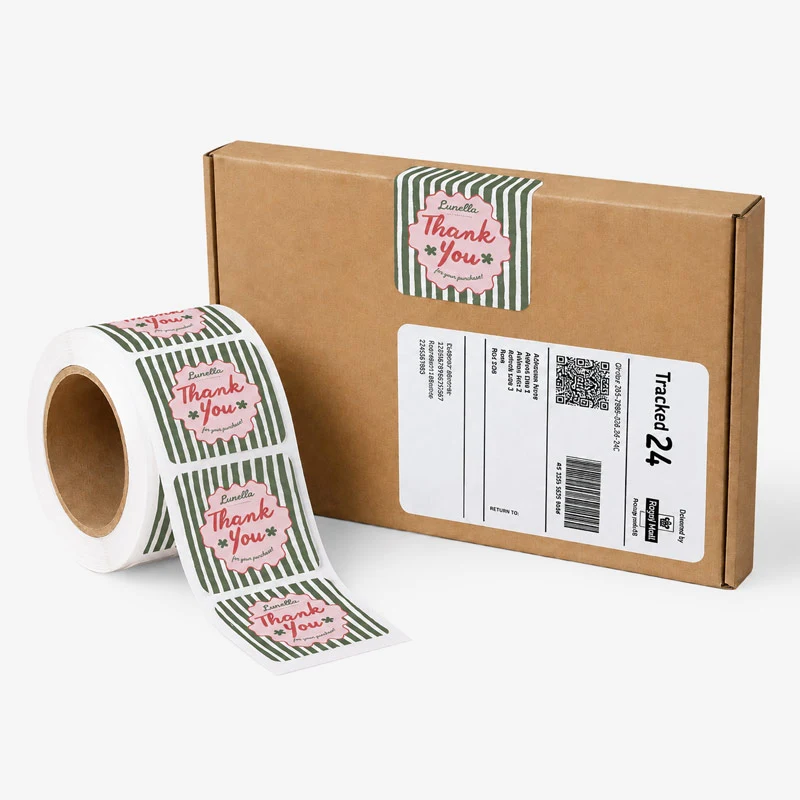 A brown box with a shipping label and a "Thank You" sticker; a roll of similar stickers nearby.