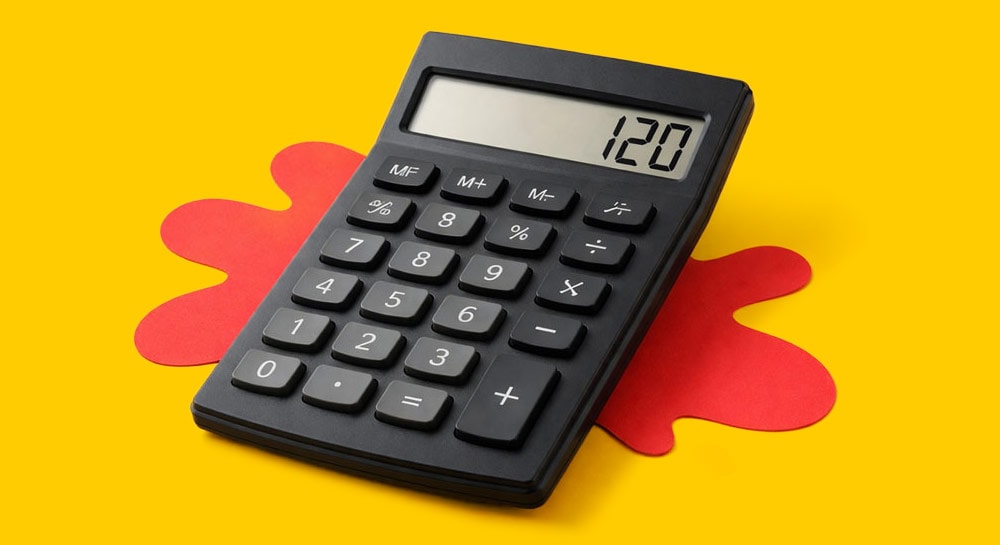 Black calculator displaying 120 on screen, placed on a yellow background with a red shape.