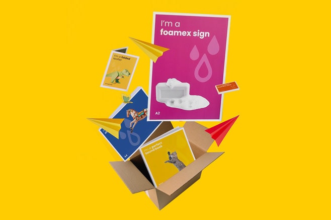 A box with colourful printed materials, posters, and paper airplanes on a yellow background.