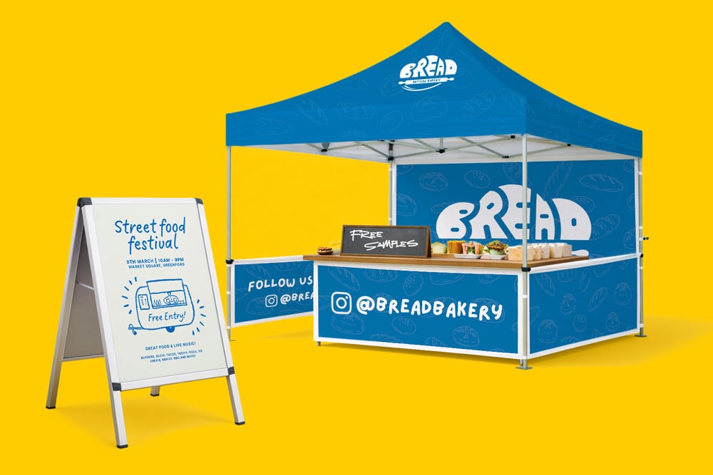 Blue Bread Bakery booth with food samples and a street food festival sign on a yellow background.