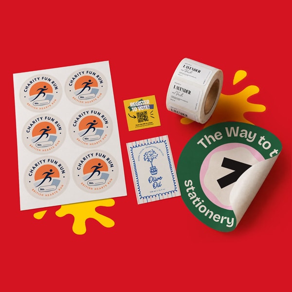 Assorted colorful stickers and labels arranged on a bright red background with yellow paint splash.