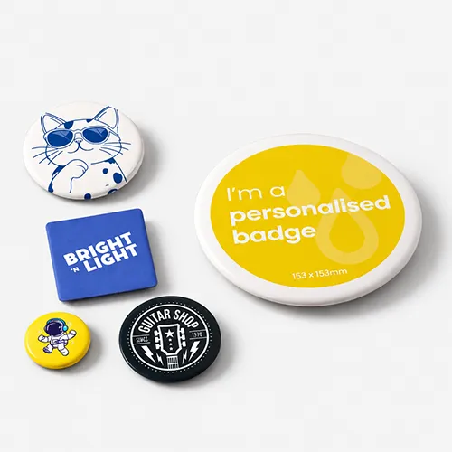 Six assorted badges with different designs and text displayed on a light grey surface.