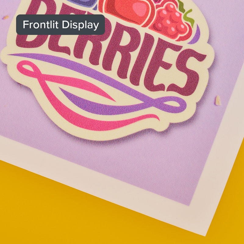 Close-up of a colorful "BERRIES" sticker on a purple background with "Frontlit Display" label.