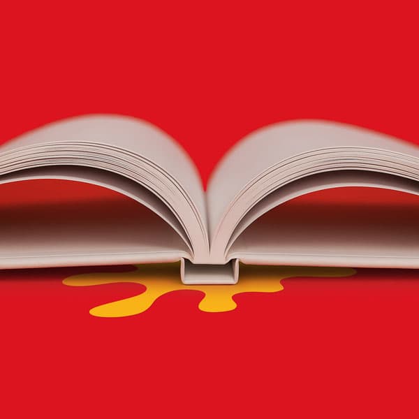 Open book on a red surface with a yellow splatter shape beneath its center.