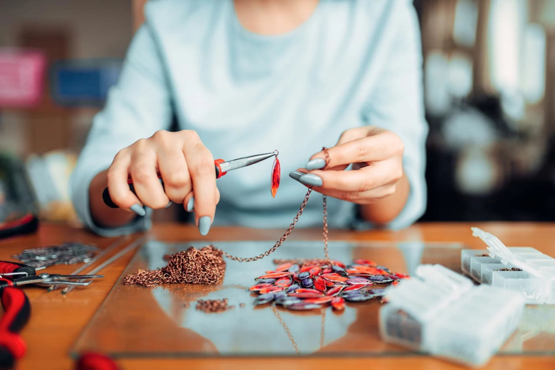 A woman meticulously works on a necklace, using scissors to refine the materials in her hands