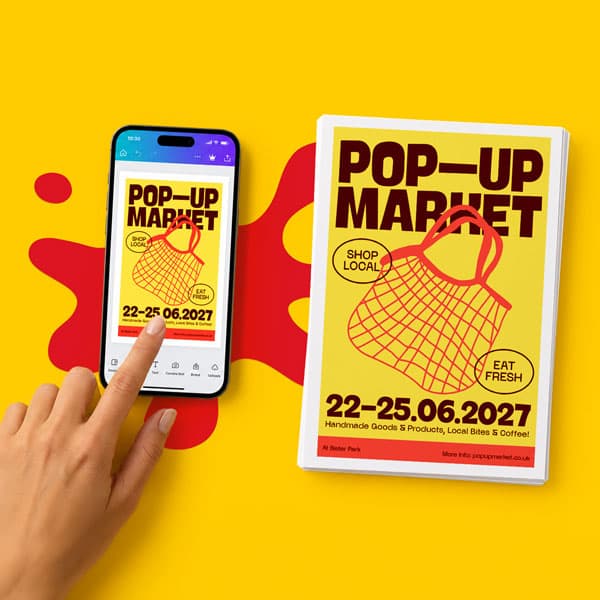 A hand touches a phone showing a pop-up market poster next to a matching printed flyer.