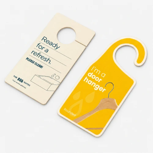 Two door hangers, one beige with text and one yellow with a hanger graphic, on a gray surface.