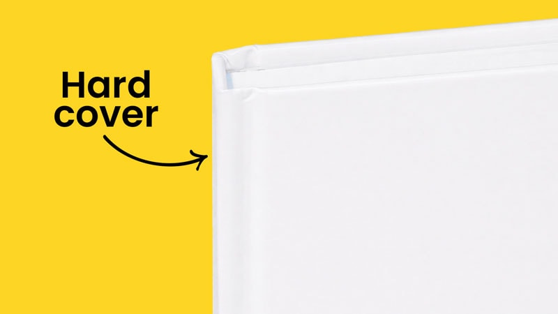 Close-up of a white hardcover book against a yellow background with a "Hard cover" label.