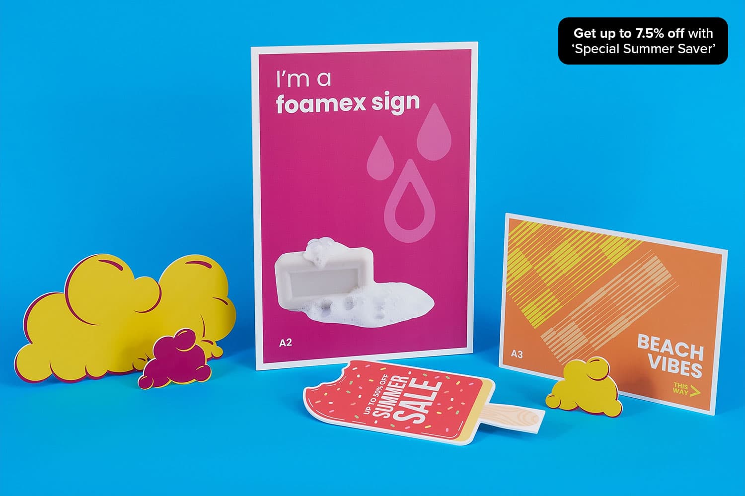 Various colourful printed signs and cutouts displayed on a blue surface, advertising up to 7.5% off as part of a Summer Savers campaign.