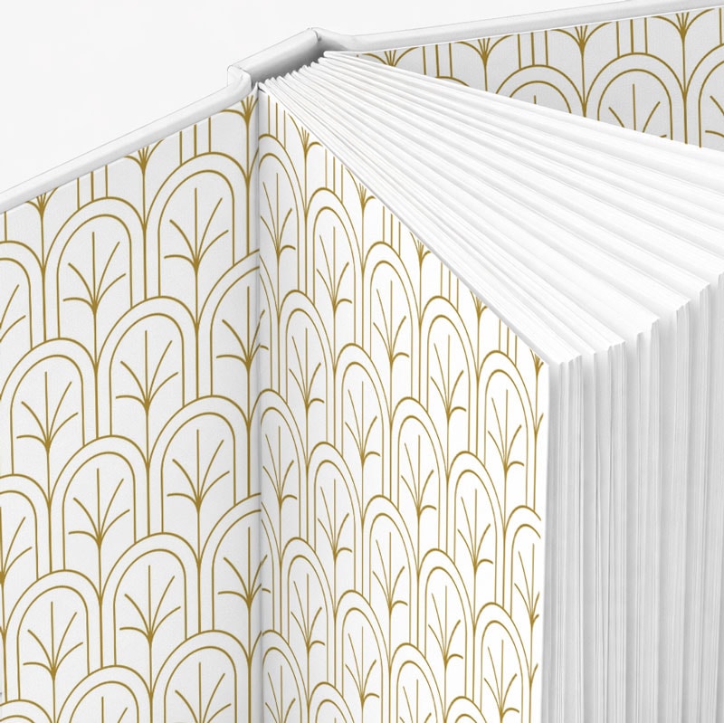 Open hardcover book with white and gold geometric patterned endpapers and blank pages.