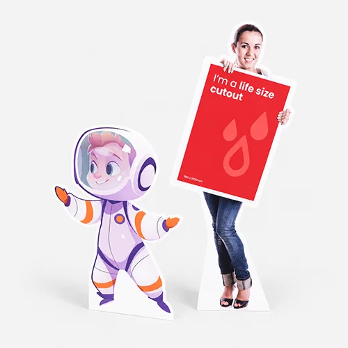 Life size standee of a woman holding a red sign next to a cartoon astronaut life-size cutout on a white background.