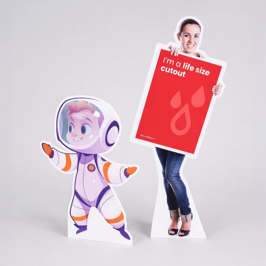 Life size standee of a woman holding a red sign next to a cartoon astronaut life-size cutout on a white background.