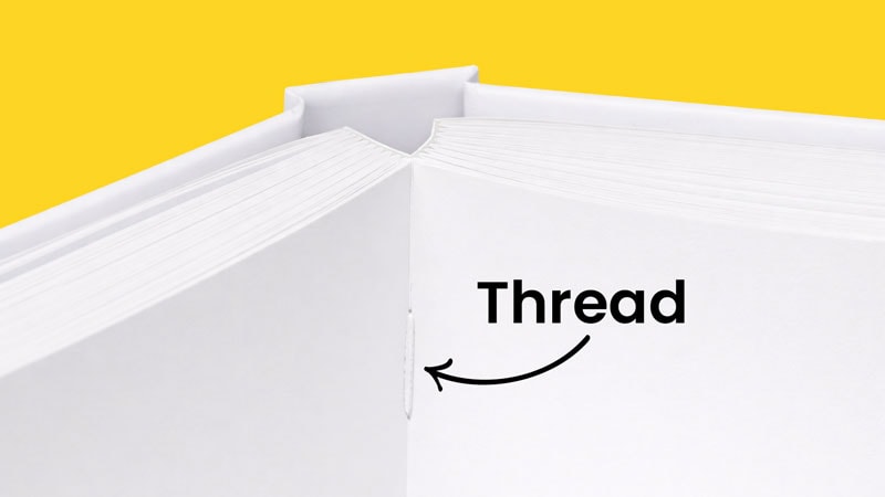 Close-up of an open hardcover book showing a sewn thread binding inside the spine.