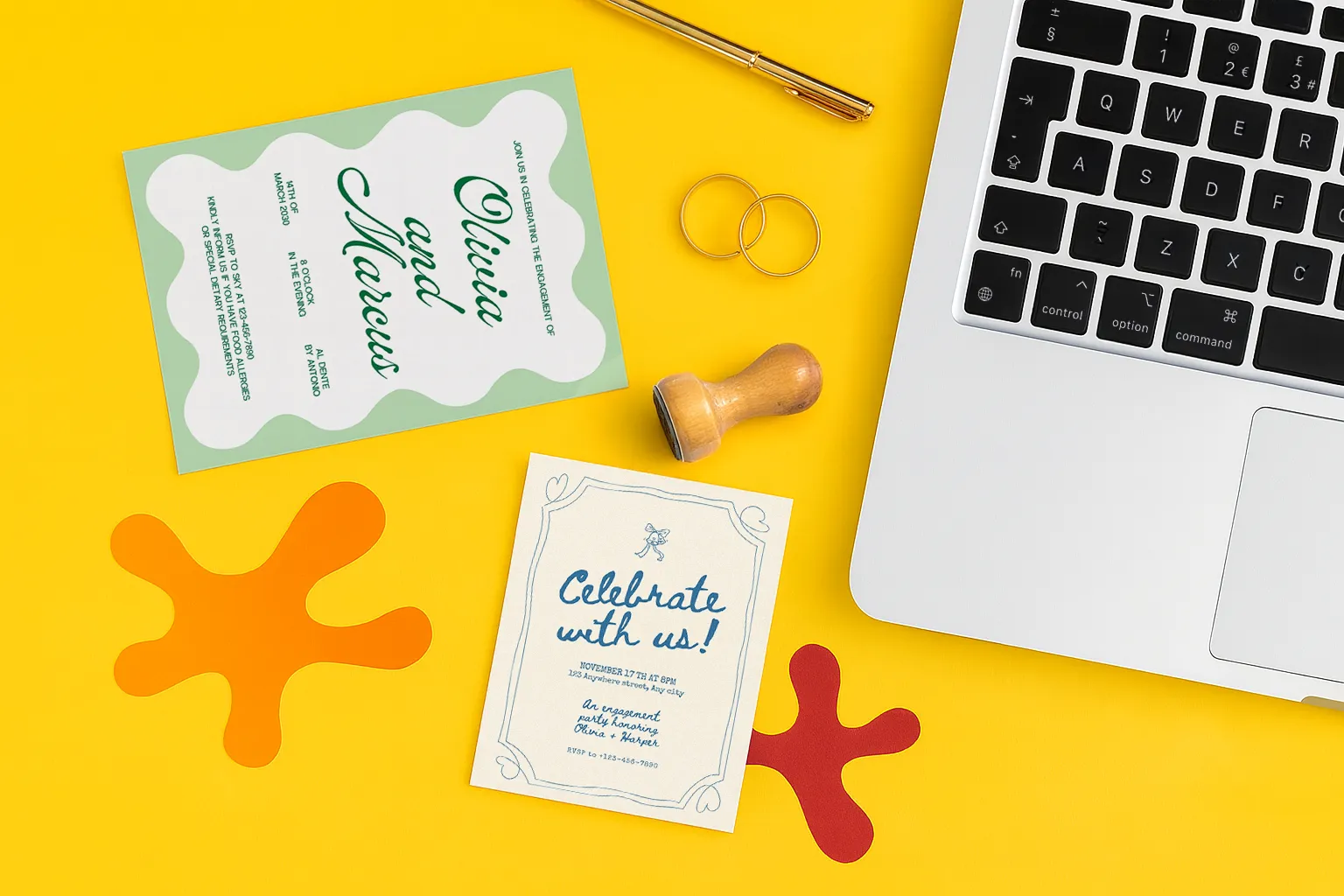 Wedding stationery, rings, pen, and laptop on a yellow desk with colourful ink shapes.