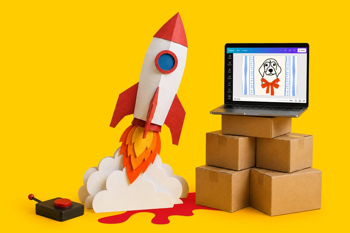 Paper rocket and joystick beside a laptop on boxes, with a dog graphic on the screen, on yellow.
