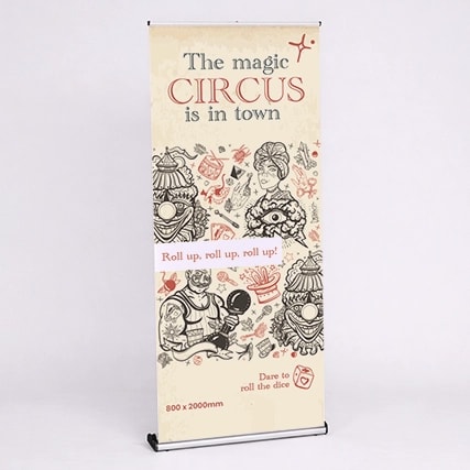 A circus-themed banner stand with illustrations and text promoting "The magic CIRCUS is in town.