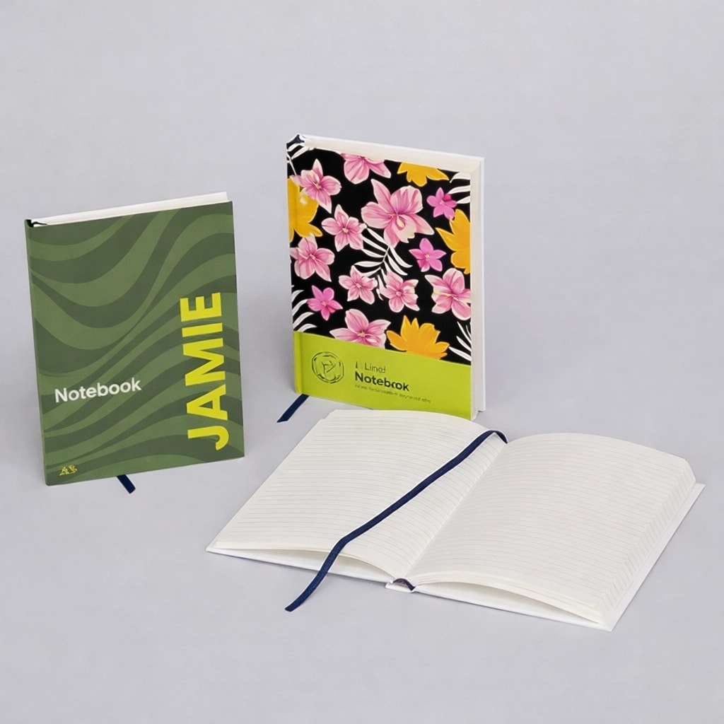 Three notebooks: one green with "JAMIE," one floral, and one open displaying lined pages.