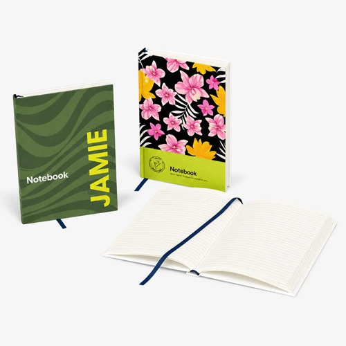 Three notebooks: one green with "JAMIE," one floral, and one open displaying lined pages.