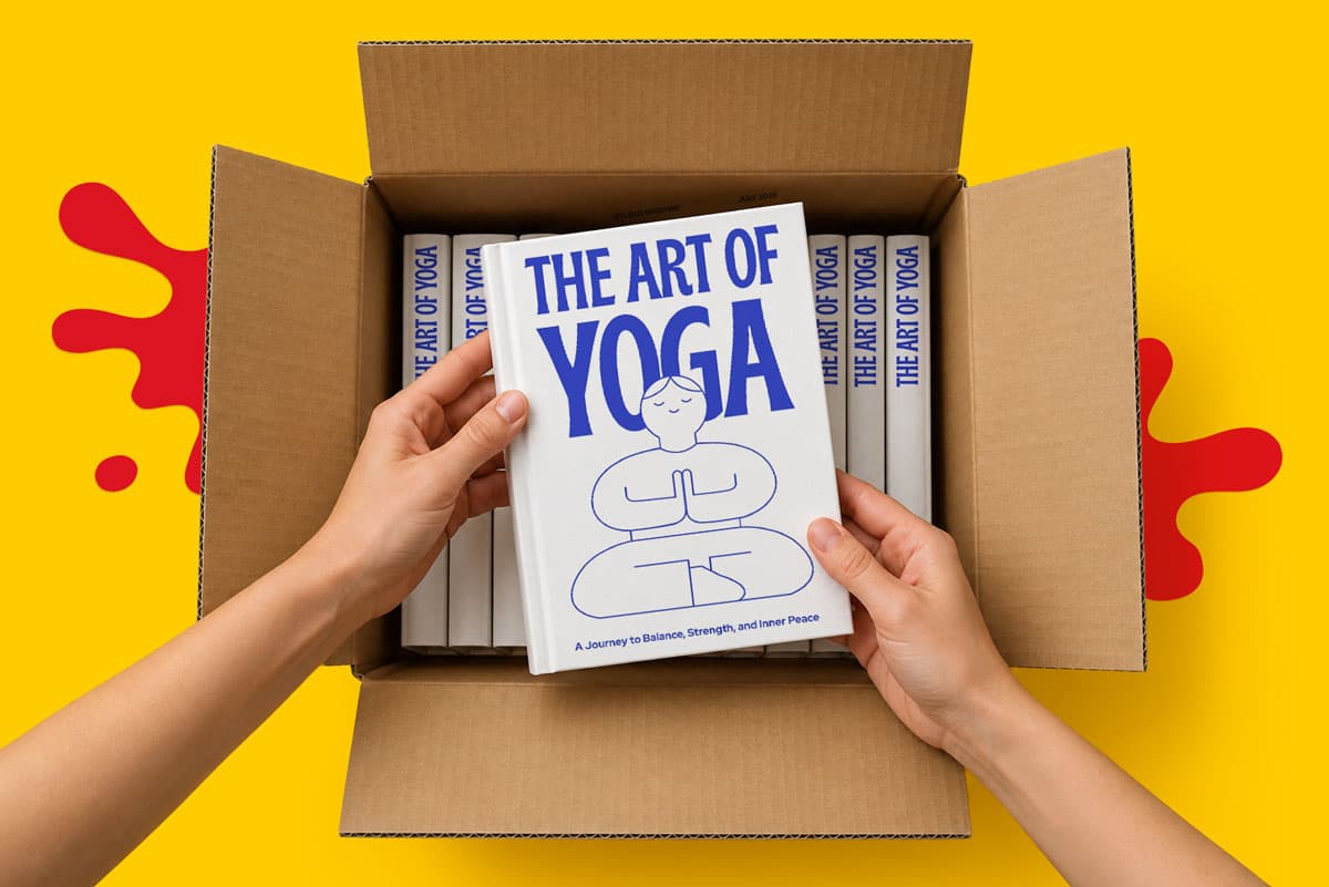 Hands holding “The Art of Yoga” book above a box filled with identical books on a yellow background.