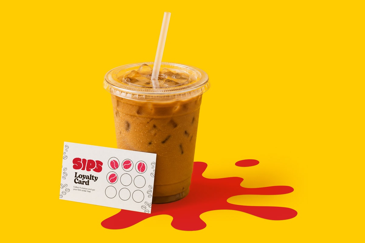 Iced coffee in plastic cup with straw next to a SIPS loyalty card on a yellow background.
