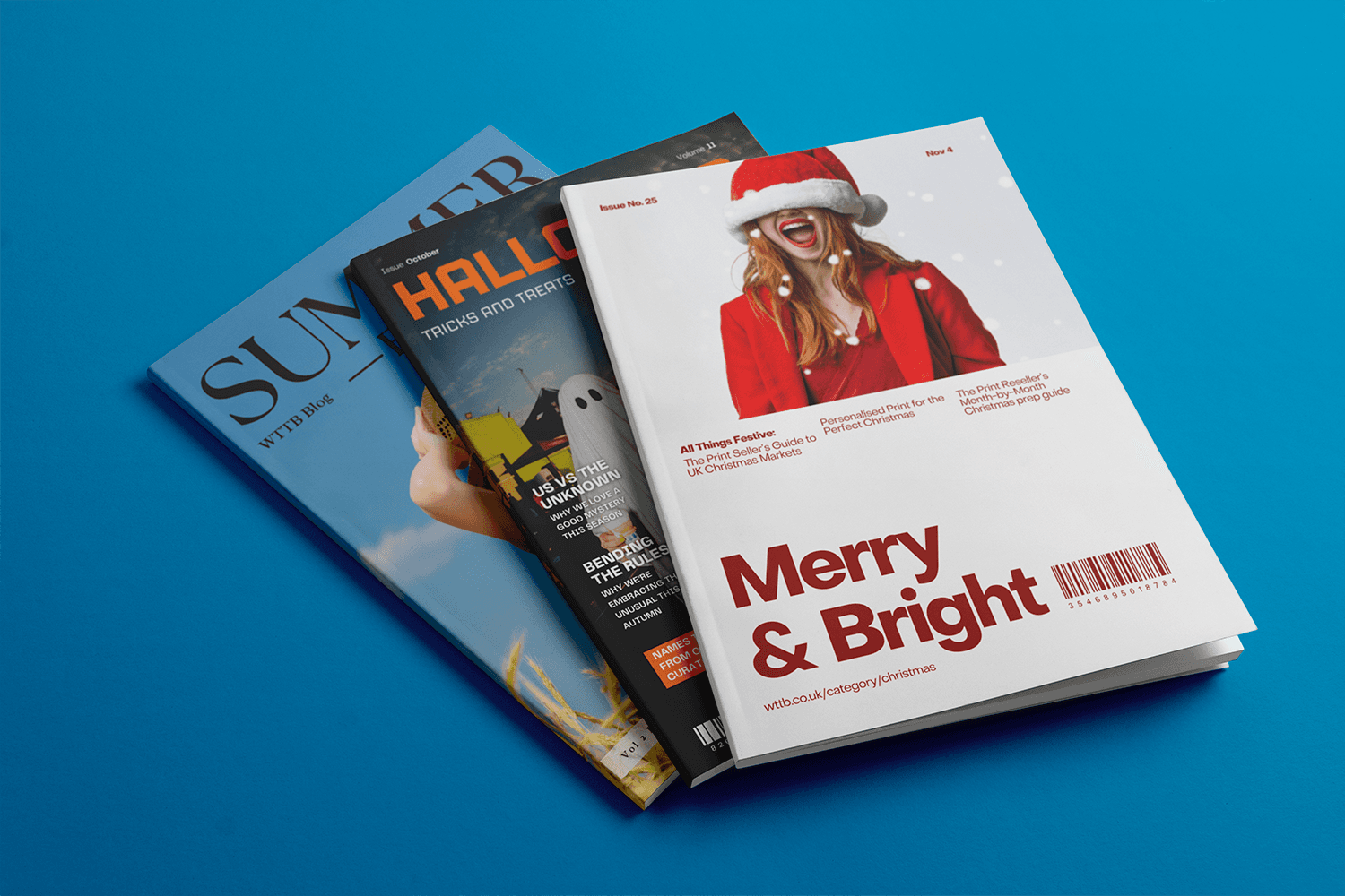 Three magazines stacked on a blue surface, with the top one featuring a woman in a Santa hat.