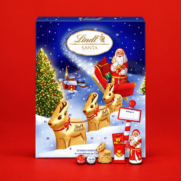 Lindt Santa chocolate advent calendar with assorted chocolate pieces in front.