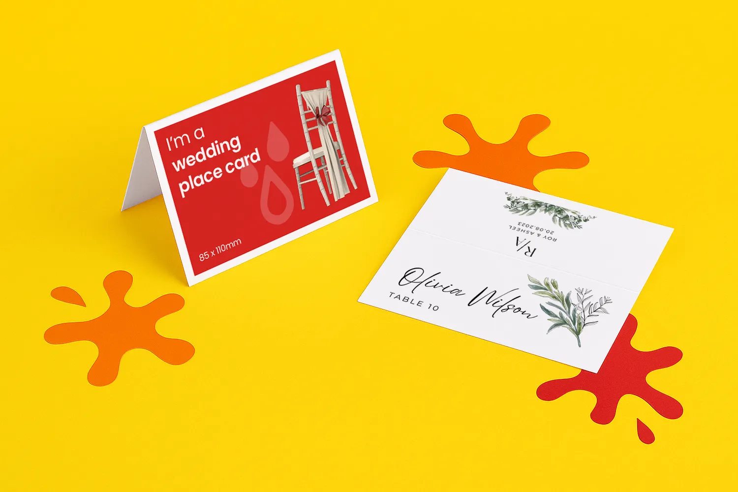 Two wedding place cards displayed on a yellow surface with orange decorative splashes.
