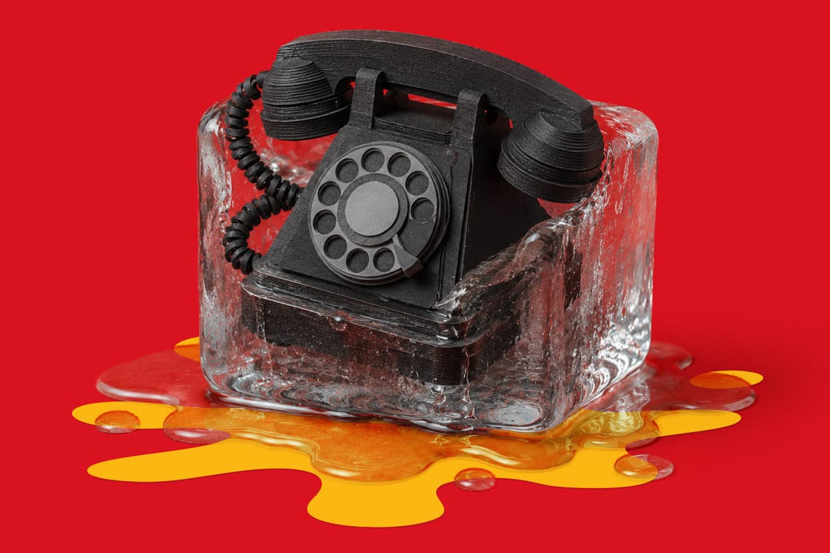 A black rotary phone frozen in a melting ice block against a red background.