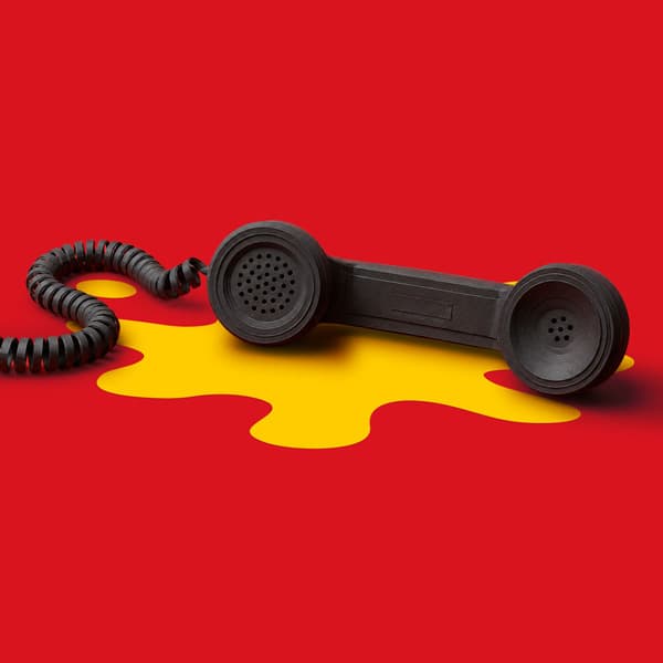 Black corded phone handset on yellow paint spill against a red background.