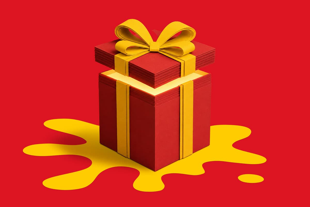 Red gift box with yellow ribbon and bow on a yellow splatter shape, on a red background.