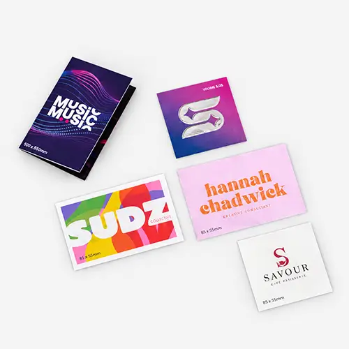 Five colourful custom business cards with various designs and company names displayed on a gray surface.