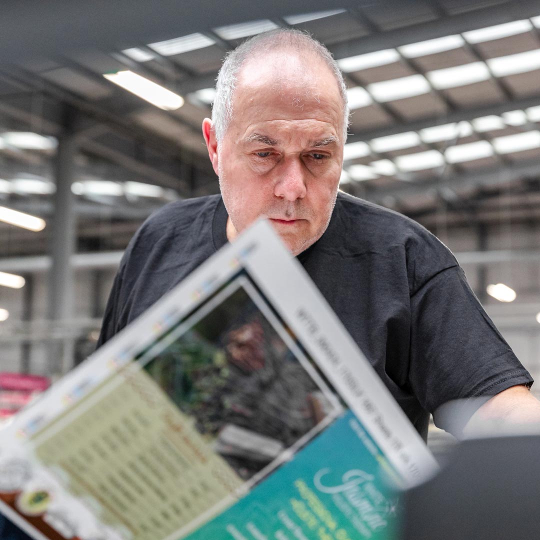 Person analysing a colourful printed sheet in a spacious, bright indoor setting.