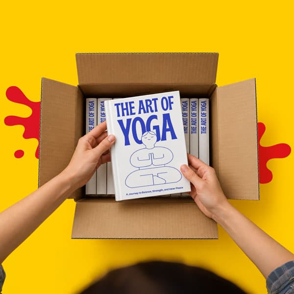 Hands holding a book titled “The Art of Yoga” above a box filled with identical books.