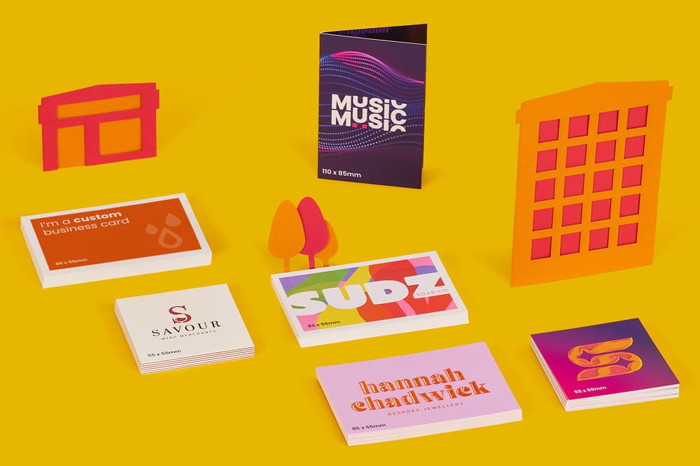 A collection of various branded business cards and small paper print materials on a yellow surface.