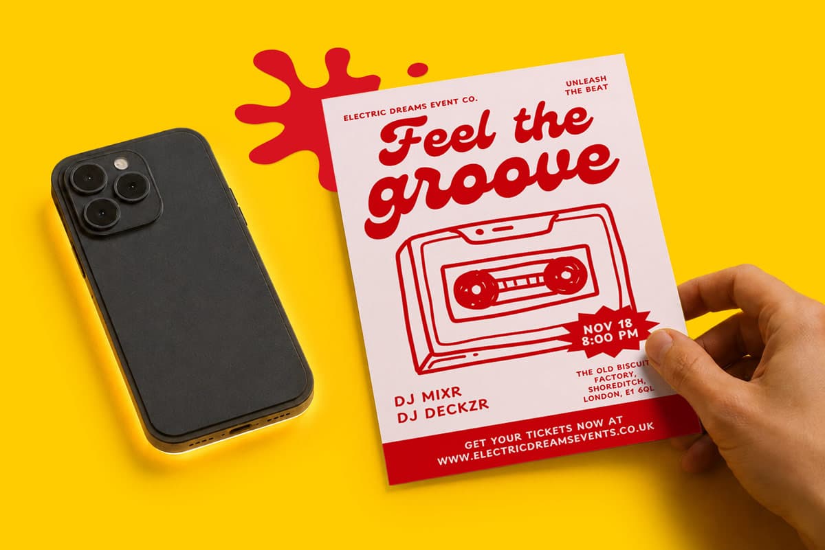 Hand holding flyer for "Feel the Groove" music event next to a black smartphone on yellow surface.