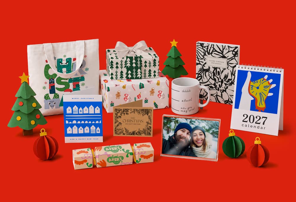 Assorted printed holiday gifts, decor, cards, and calendar arranged on a red background.