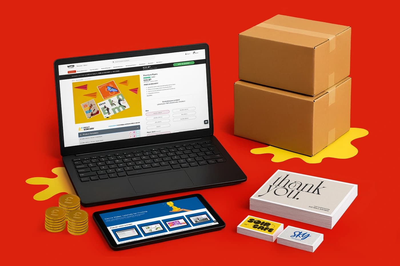 Laptop, tablet, boxes, cards, stickers, and coins displayed on a red surface.