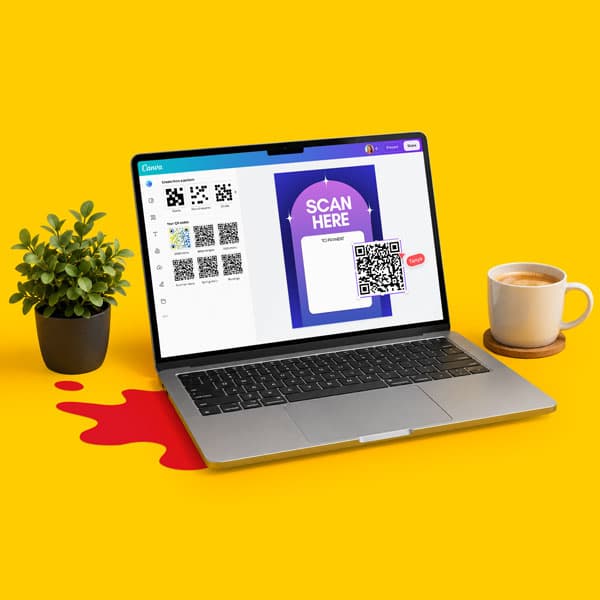 Laptop displaying QR codes on screen, next to a plant and a cup of coffee on a yellow surface.