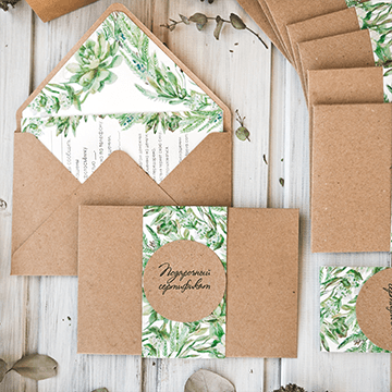 Elegant wedding invitations adorned with green leaves, showcasing a natural and sophisticated design