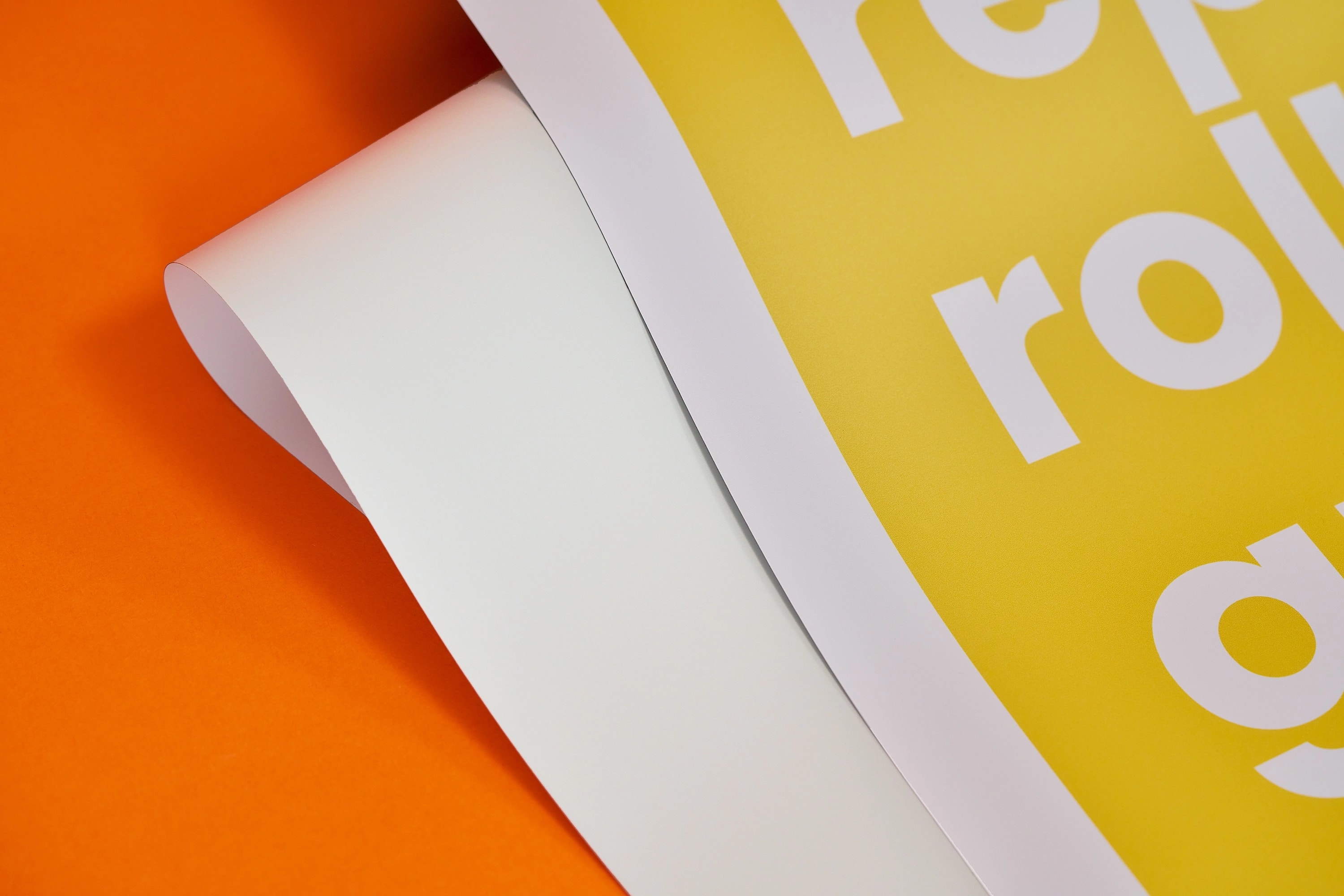A close-up of a curled yellow and white poster on an orange background.